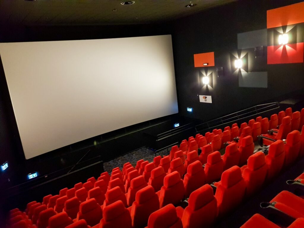 an empty theater with red seats and a projector screen